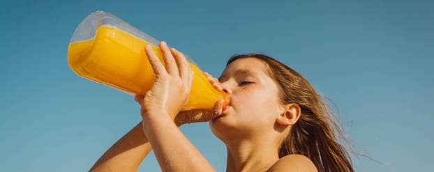 Meisje drinkt uit fles met vruchtendrank