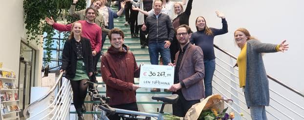 Lennart biedt cheque aan omringt door medewerkers van het Diabetes Fonds