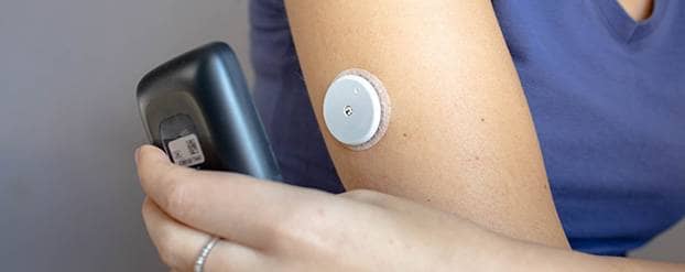 Vrouw scant continue glucose monitor op arm