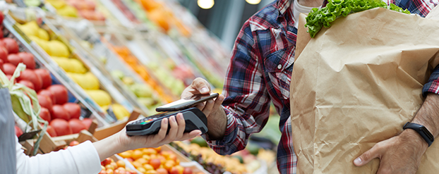 Tips om gezond en goedkoop te eten, iemand rekent af met mobiel bij de groenteboer