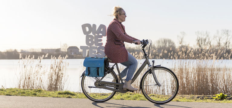 Foto vrouw met letters diabetes als ballast op de fiets