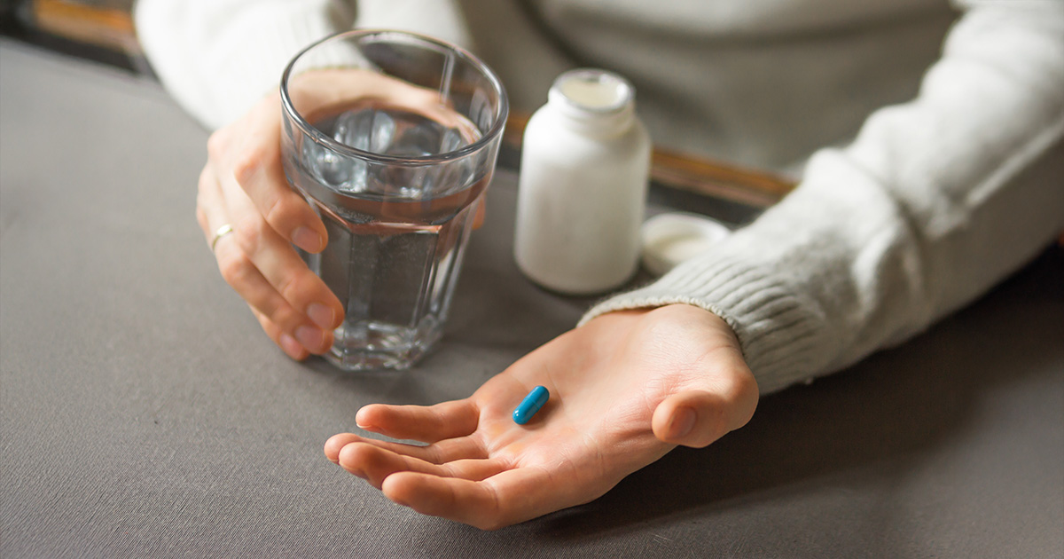 Iemand houdt blauwe pil vast in zijn hand