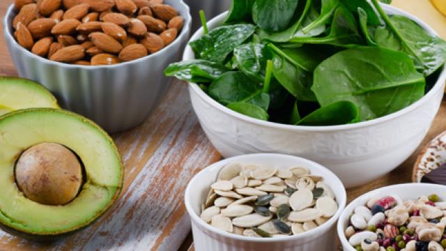 Een compositiefoto van bananen, pure chocolade, avocado, opgesteld met schaaltjes vol gezonde voeding: spinazie, amandelen, pitten, zaden en yoghurt