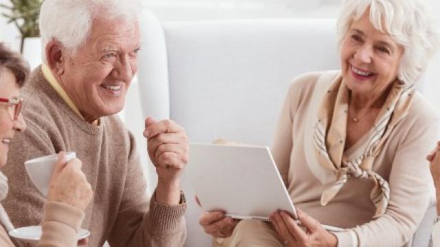 Vier ouderen drinken koffie en lachen