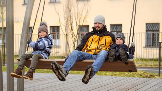 Man en kinderen op een grote schommel
