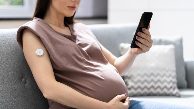 Zwangere vrouw kijkt op haar mobiele telefoon