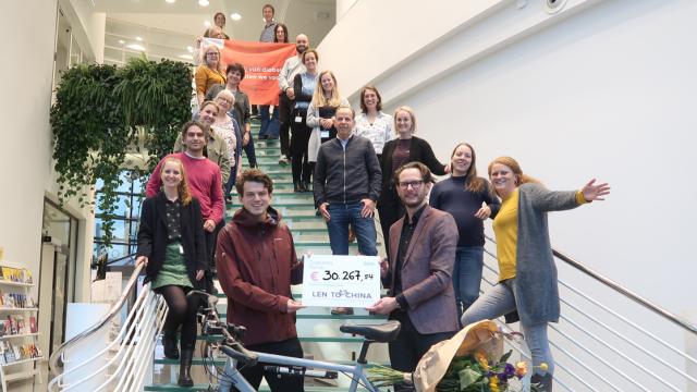 Lennart biedt cheque aan omringt door medewerkers van het Diabetes Fonds