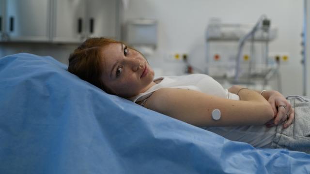 Vrouw met glucosesensor ligt op ziekenhuisbed