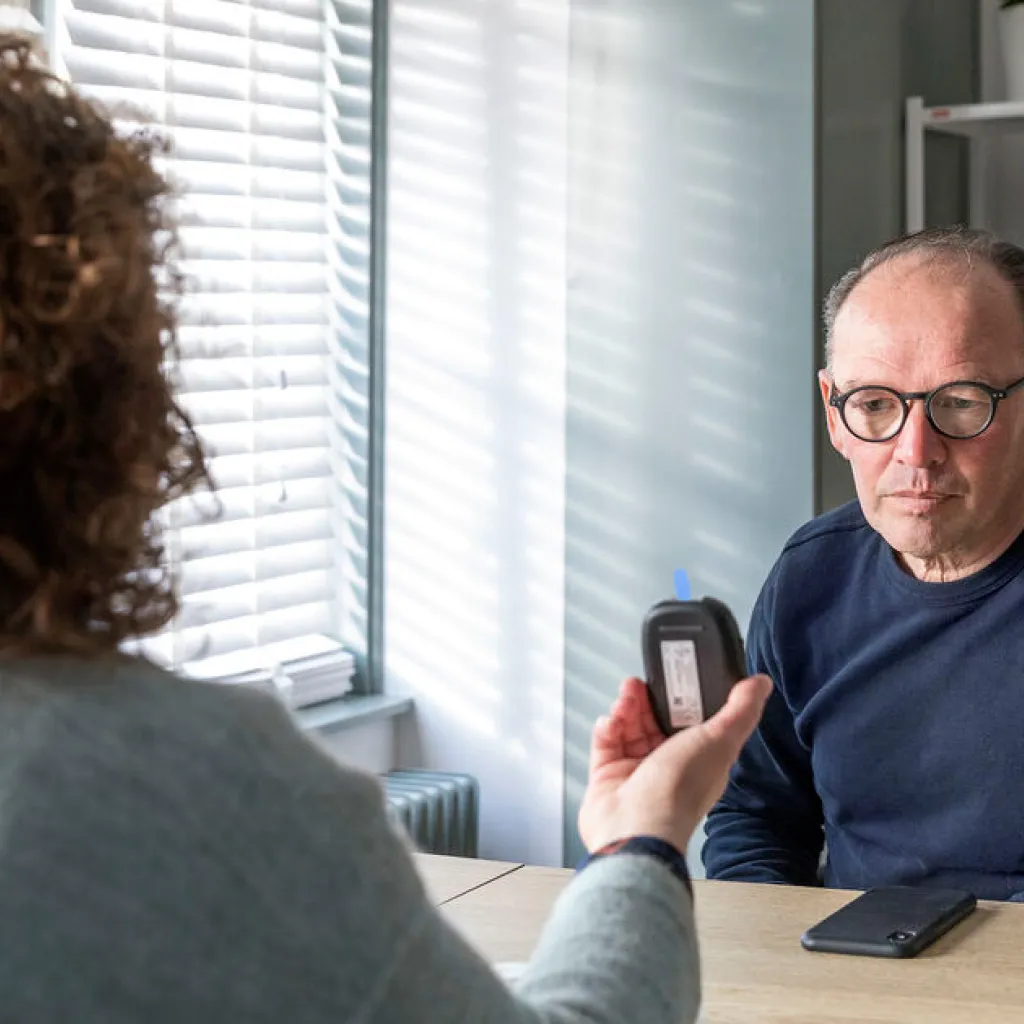 Man bij dokter die uitslag bloedtest toont