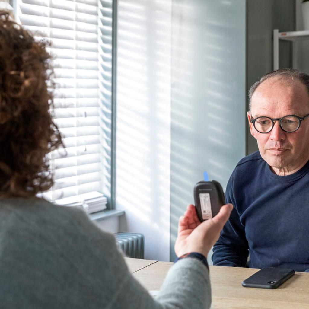 Man bij dokter die uitslag bloedtest toont
