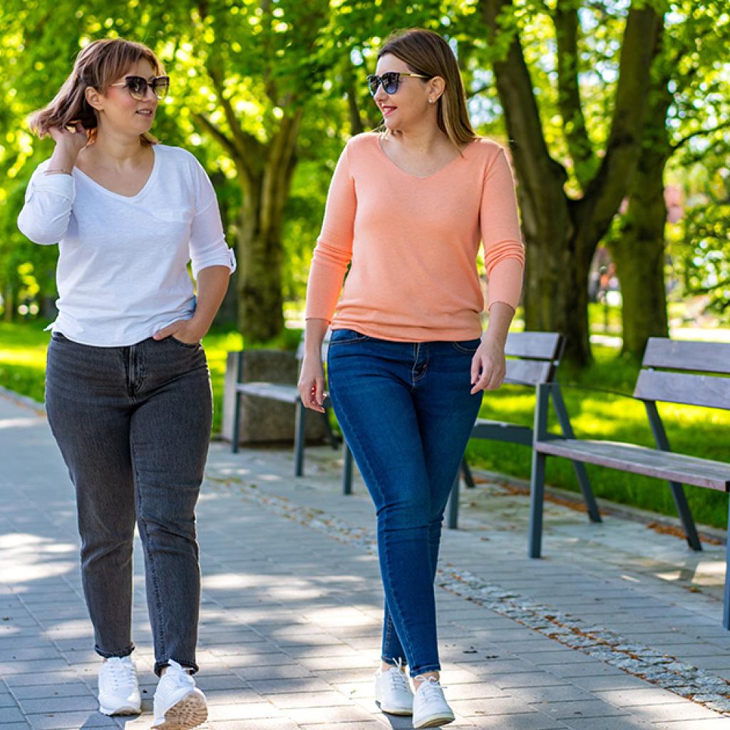 Twee vrouwen wandelen door de stad langs een park