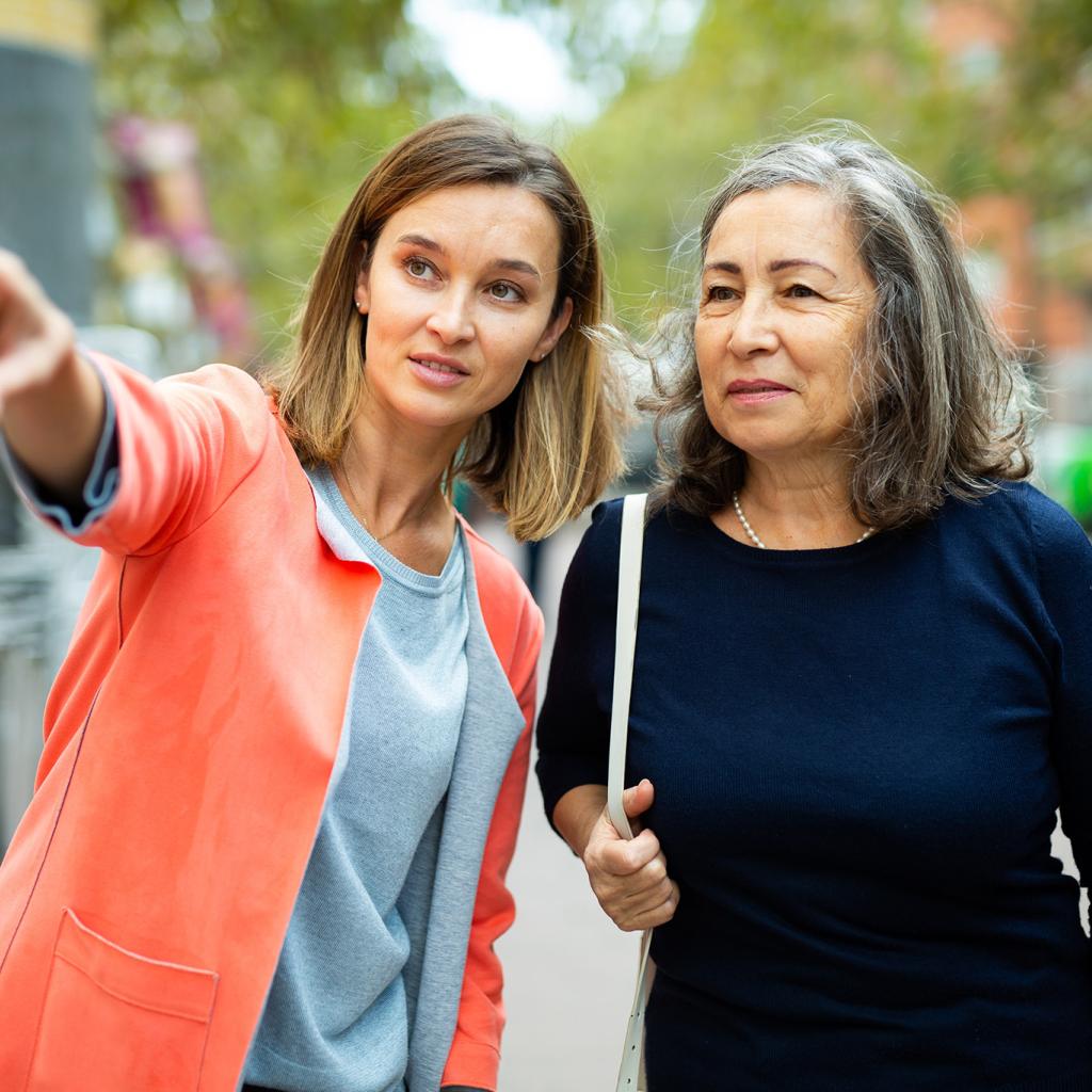 Vrouw wijst andere vrouw de weg op straat