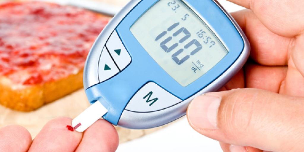 Een hand waarbij één van de vingers een druppel bloed heeft, terwijl de andere hand een glucosemeter vasthoudt die de bloedsuikerwaarde meet.