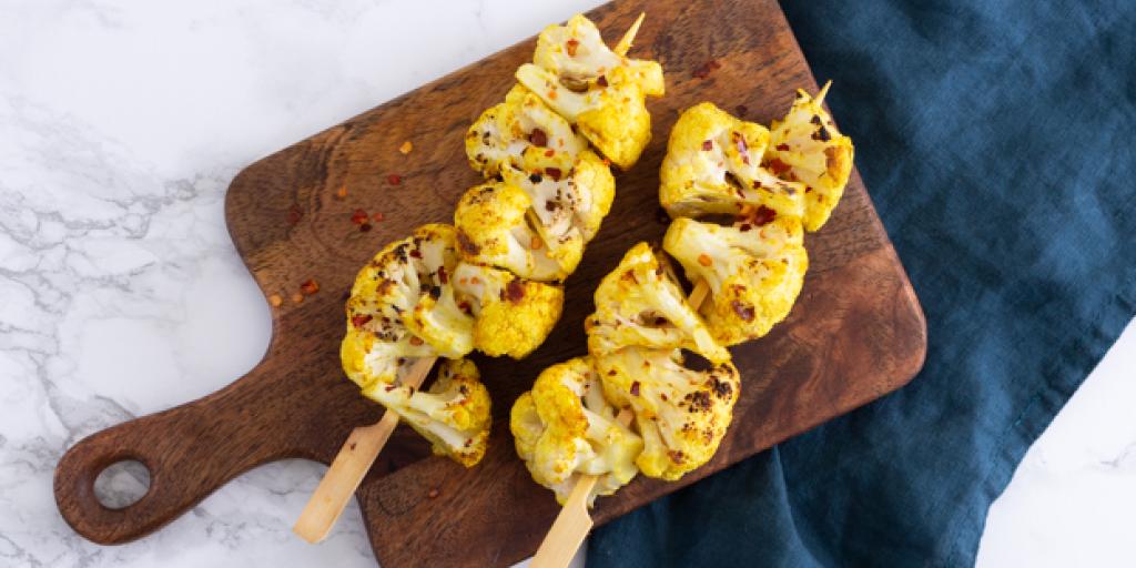 Foto van de bloemkoolspiesjes op een bruine plank