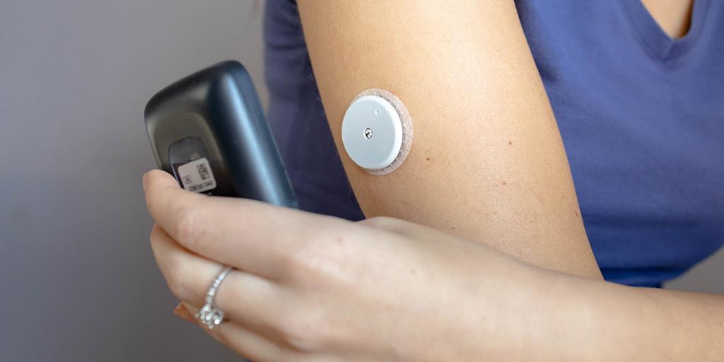 Vrouw scant continue glucose monitor op arm