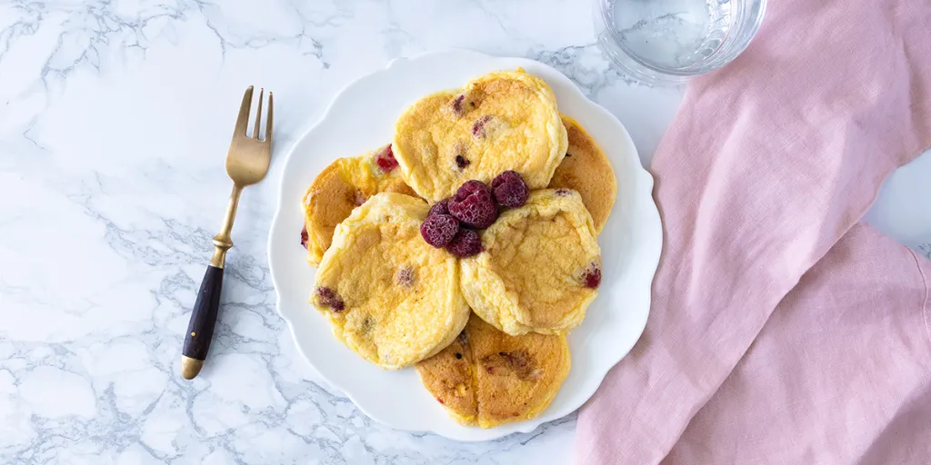 Wit bord gevuld met luchtige omeletjes en frambozen