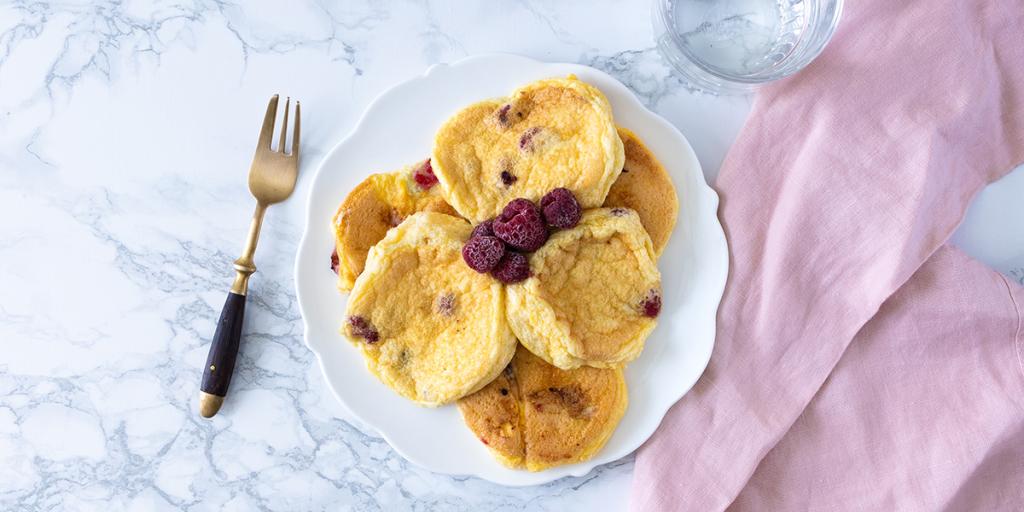 Wit bord gevuld met luchtige omeletjes en frambozen