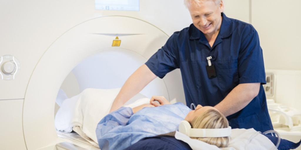 Een vrouw gaat met een koptelefoon op een MRI-scan in, terwijl de arts haar in het apparaat schuift.