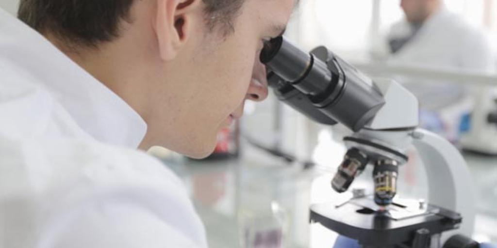 Foto: onderzoeker kijkt door microscoop