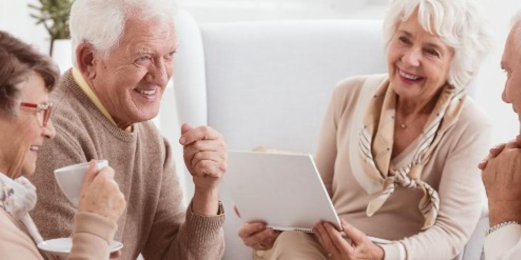 Vier ouderen drinken koffie en lachen