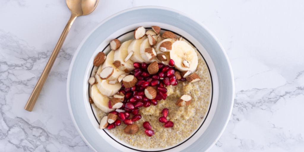Foto van de quinoa-ontbijtpap gegarneerd met schijfjes banaan, amandel en granaatappelpitjes