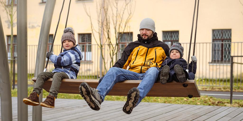Man en kinderen op een grote schommel