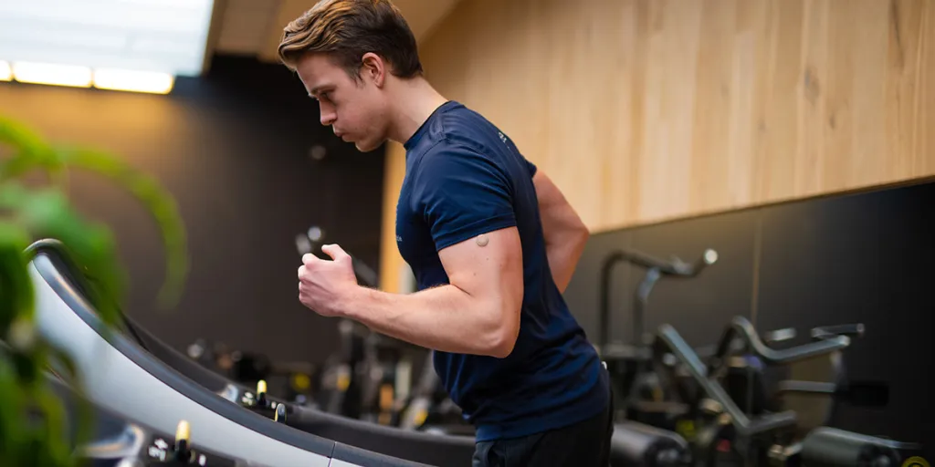 Man met sensor op zijn arm rent op de loopband