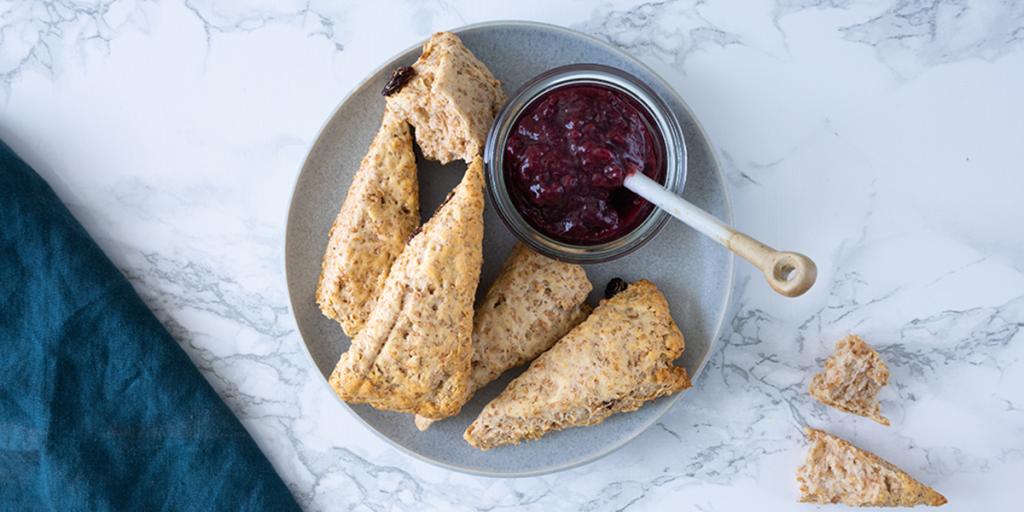 Volkoren scones op een bord met een bakje jam zonder toegevoegde suikers ernaast