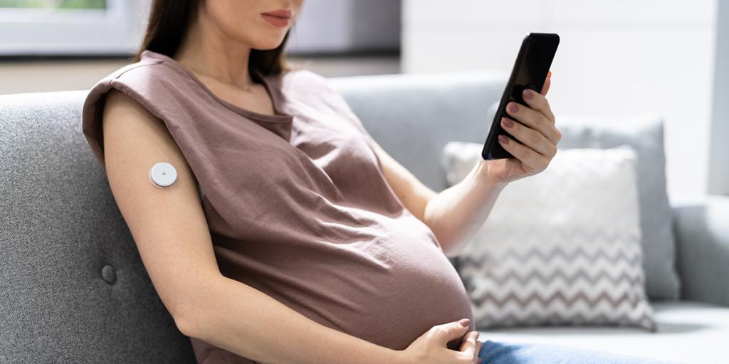 Zwangere vrouw kijkt op haar mobiele telefoon