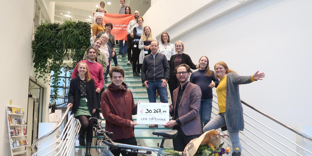 Lennart biedt cheque aan omringt door medewerkers van het Diabetes Fonds