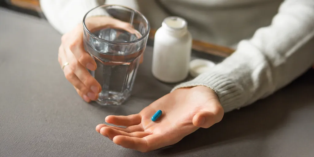 Iemand houdt blauwe pil vast in zijn hand