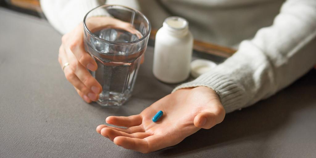 Iemand houdt blauwe pil vast in zijn hand