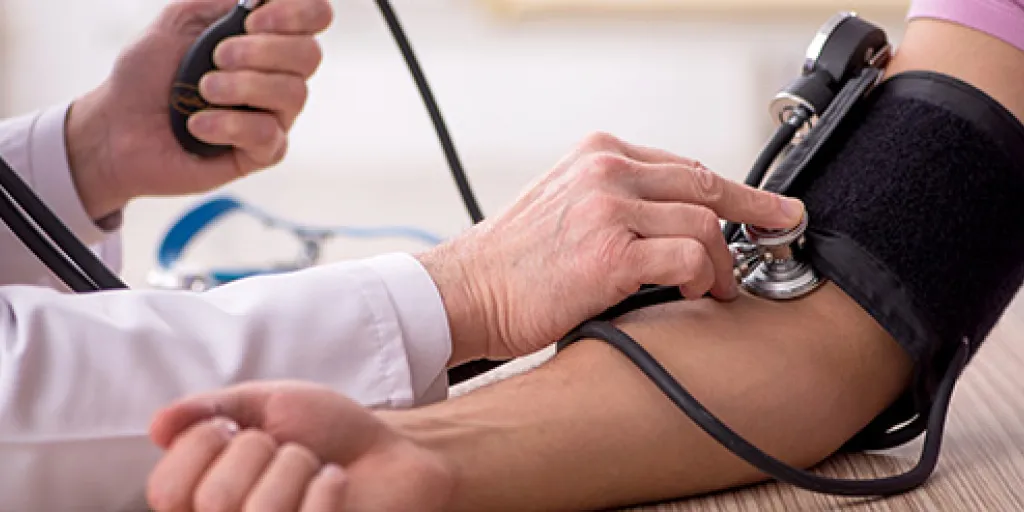 dokter meet bloeddruk op bij patient