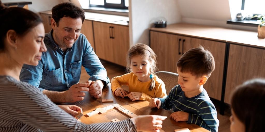 Gezin met drie kinderen doet een spelletje aan tafel