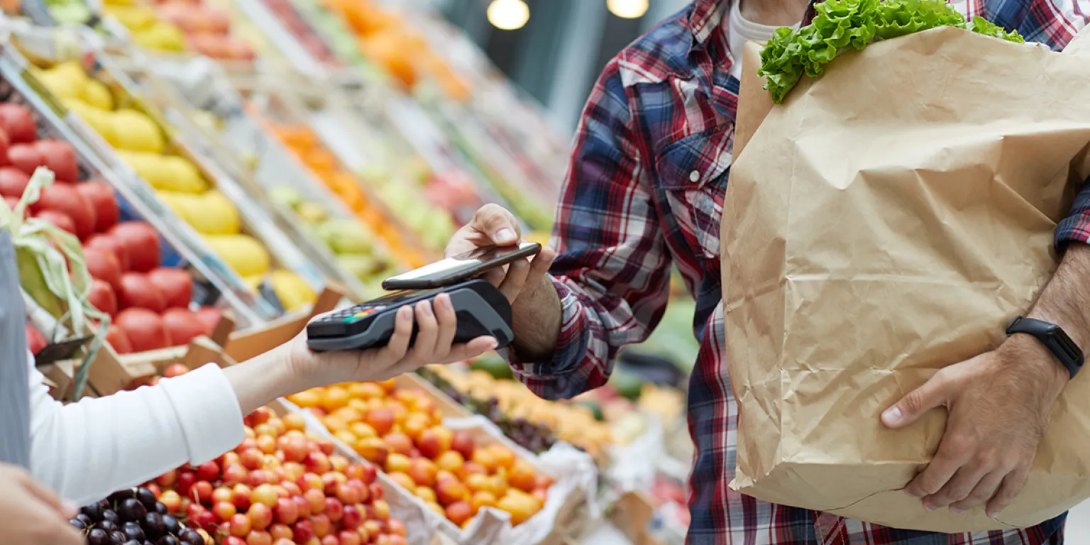 Tips om gezond en goedkoop te eten, iemand rekent af met mobiel bij de groenteboer