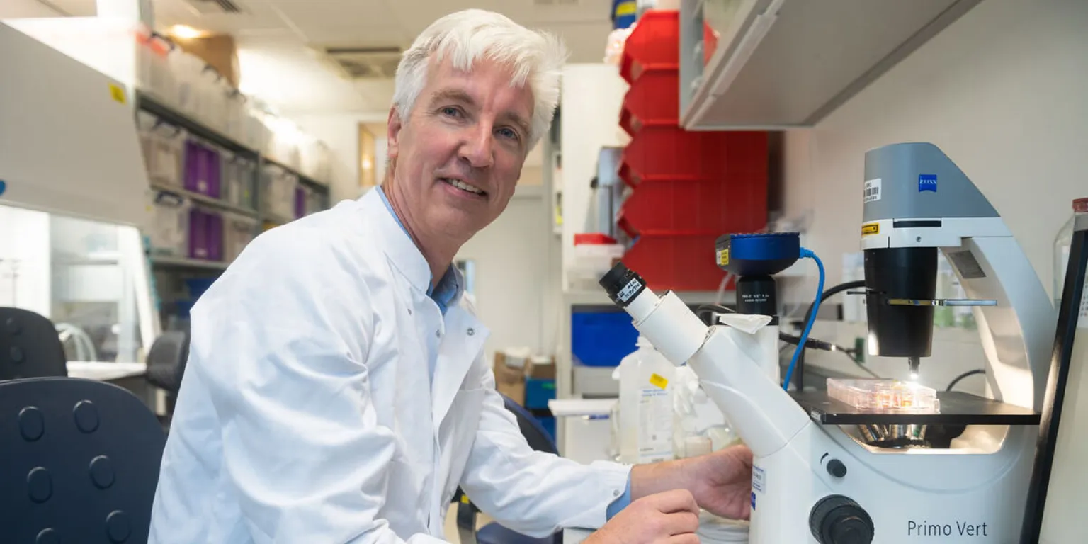 Professor dr. Eelco de Koning zit bij een microscoop