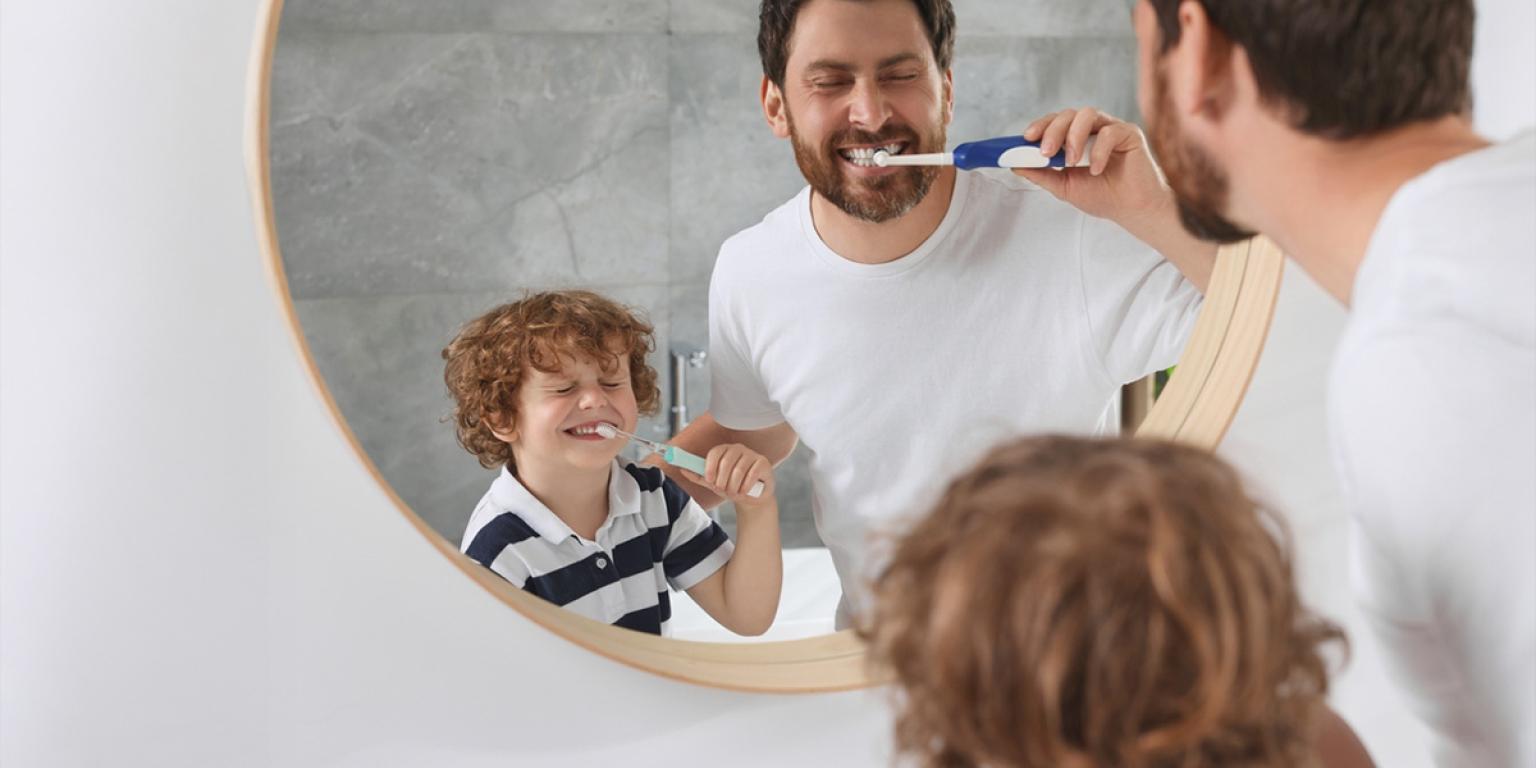 Vader en zoon poetsen tanden voor de spiegel