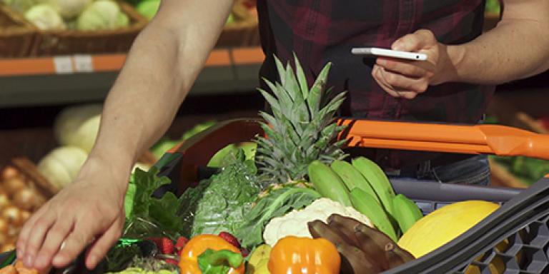 Een man die op een mobiel kijkt in een omgeving van gezonde voeding