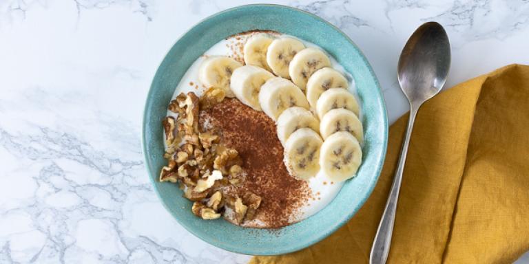 Foto kwark met banaan, cacaopoeder en walnoten in een lichtblauw bakje