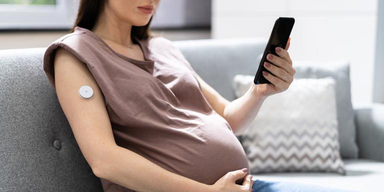 Zwangere vrouw kijkt op haar mobiele telefoon