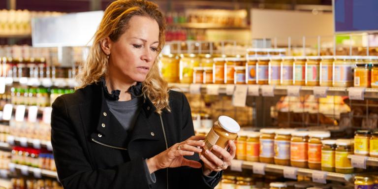 Vrouw in supermarkt checkt etiket op suiker