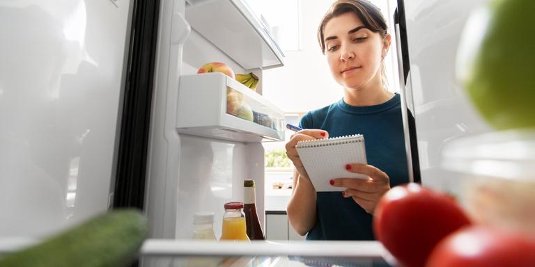 Vrouw maat zich gereed voor de Nationale Suiker Challenge en controleert de koelkast