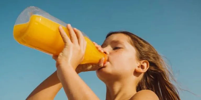 Meisje drinkt uit fles met vruchtendrank