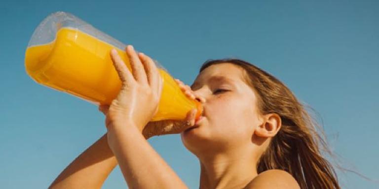 Meisje drinkt uit fles met vruchtendrank