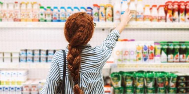 Vrouw pakt zuiveldrank in supermarkt