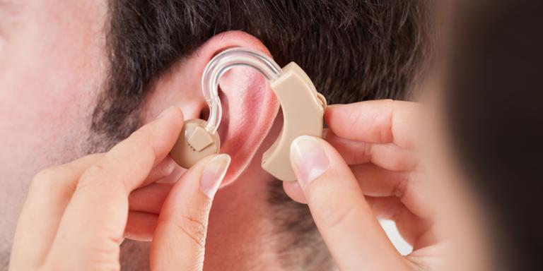 Foto: Iemand met MIDD met een gehoorapparaat