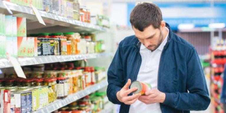 Foto van man die boodschappen doet en etiket goed leest