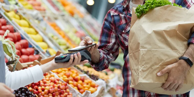 Tips om gezond en goedkoop te eten, iemand rekent af met mobiel bij de groenteboer
