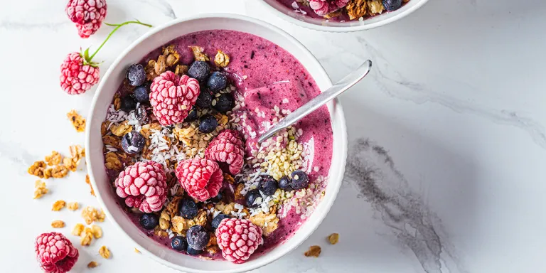 Foto vegetarisch ontbijt van smoothiebowl met frambozen, bosbessen en kokos