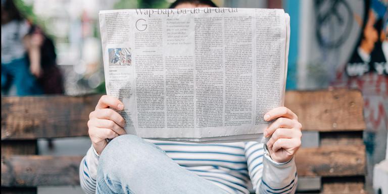 Iemand leest krant op een bankje